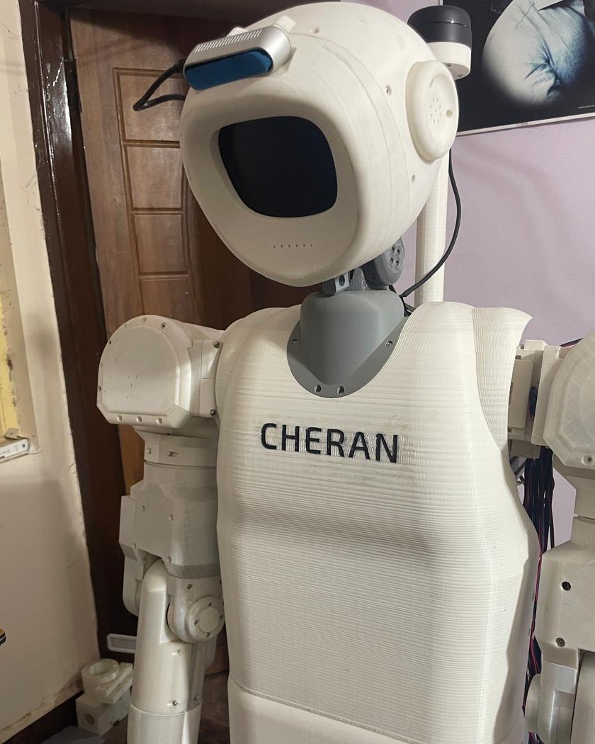 Origin, the Cheran Robotics service robot, in three-quarter view showing its head with a depth camera, the lidar mast, the Cheran name on its chest, and its arms